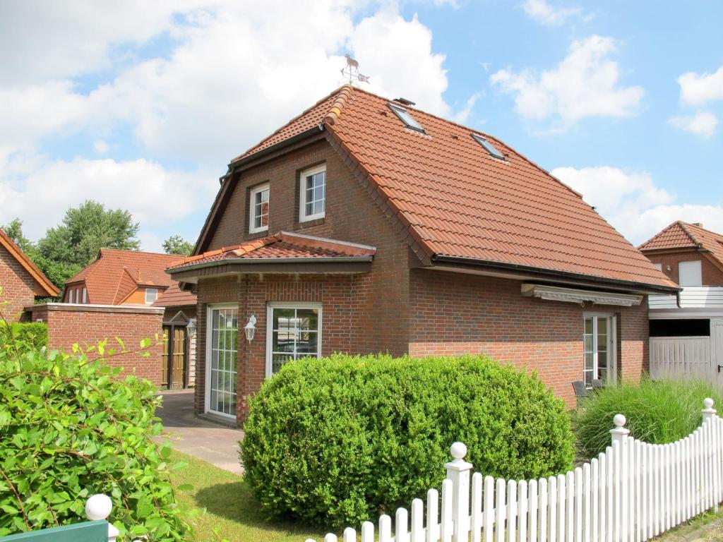 ホークジールにあるHoliday Home Christa - HOK110 by Interhomeの赤い屋根と白い柵のレンガ造りの家
