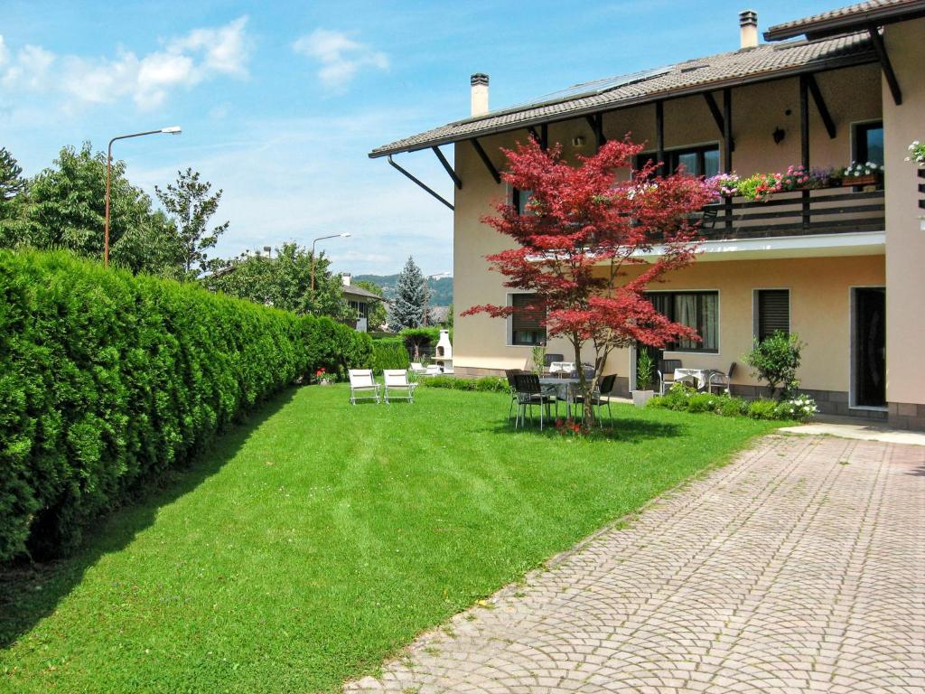 a house with a grass yard next to a building at Apartment Anna-1 by Interhome in Caldonazzo