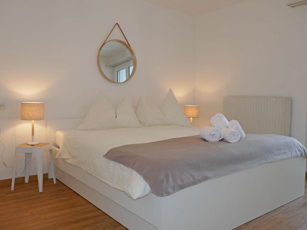 sypialnia z dużym białym łóżkiem z lustrem w obiekcie Apartment Chesa Ova Cotschna 306 by Interhome w Sankt Moritz