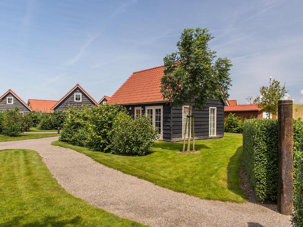 ウェーメルディンゲにあるHoliday Home Zeeuwse Cottage Wemeldinge-5 by Interhomeの木と砂利の道のある家