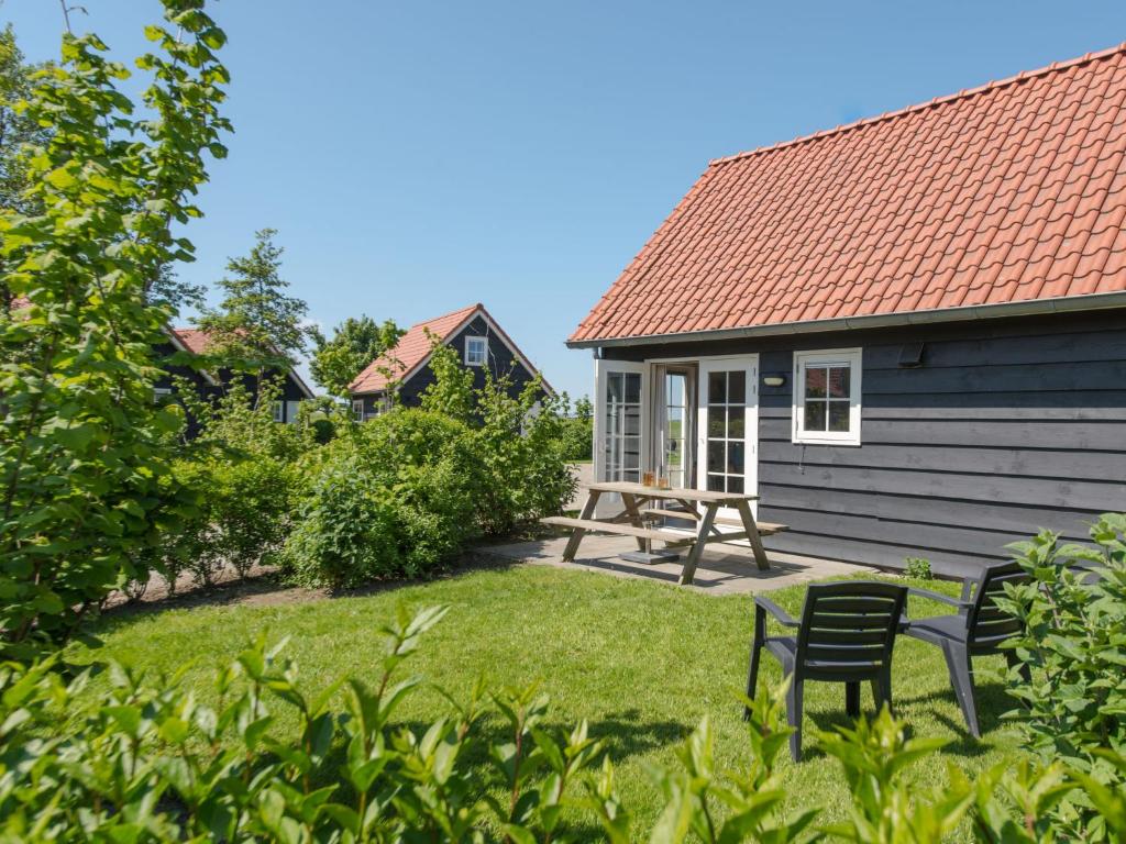 een tuin met een stoel en een huis bij Holiday Home Zeeuwse Cottage Wemeldinge-3 by Interhome in Wemeldinge