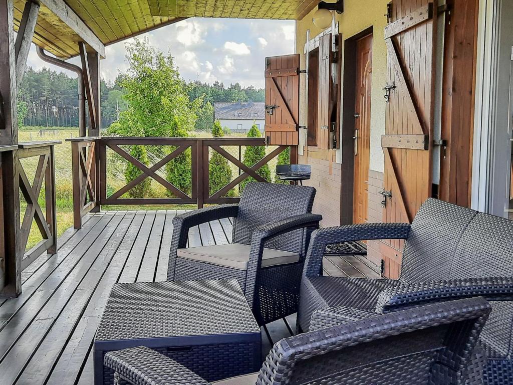 weranda z krzesłami oraz drewniany taras z ogrodzeniem w obiekcie Holiday Home Zakątek Ventus II by Interhome w Smołdzińskim Lesie