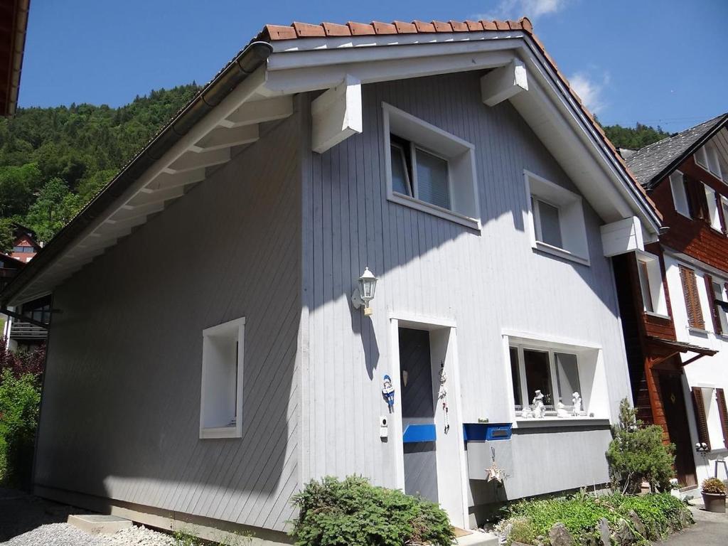 ein graues und weißes Haus mit einer Tür in der Unterkunft Apartment Bühl 13 by Interhome in Engelberg