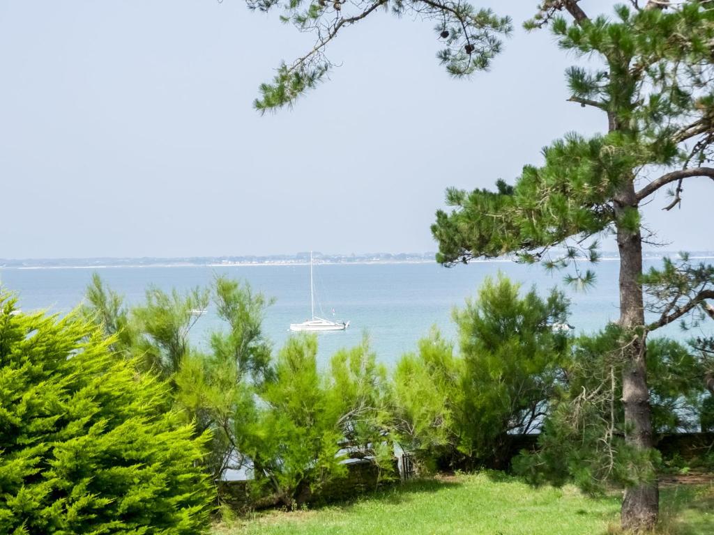 a sailboat in the water behind some trees at Holiday Home Maison Poul by Interhome in Saint-Pierre-Quiberon