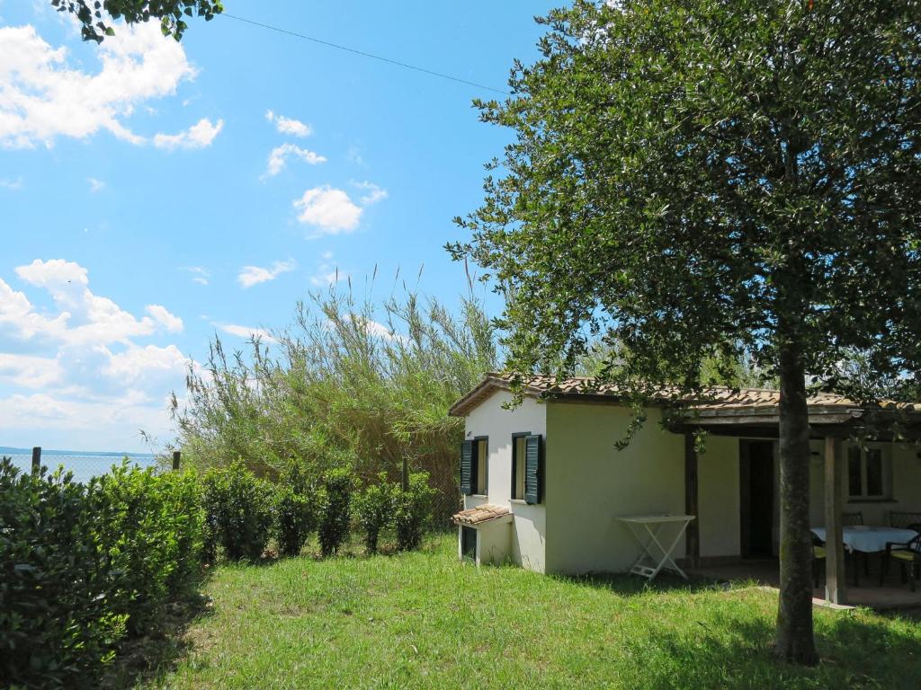 a house with a tree next to the ocean at Holiday Home Chalet del Lago by Interhome in Bolsena