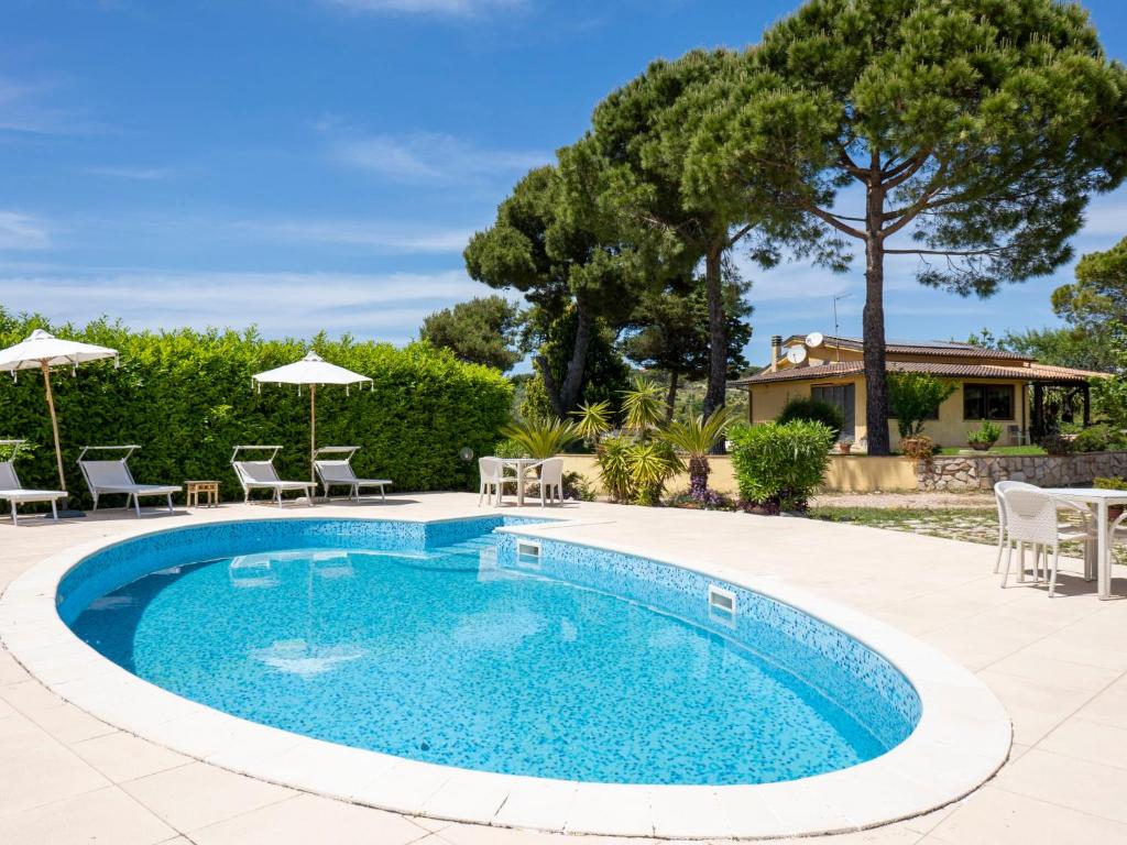 a pool with chairs and umbrellas in a yard at Apartment Saha by Interhome in Sperlonga
