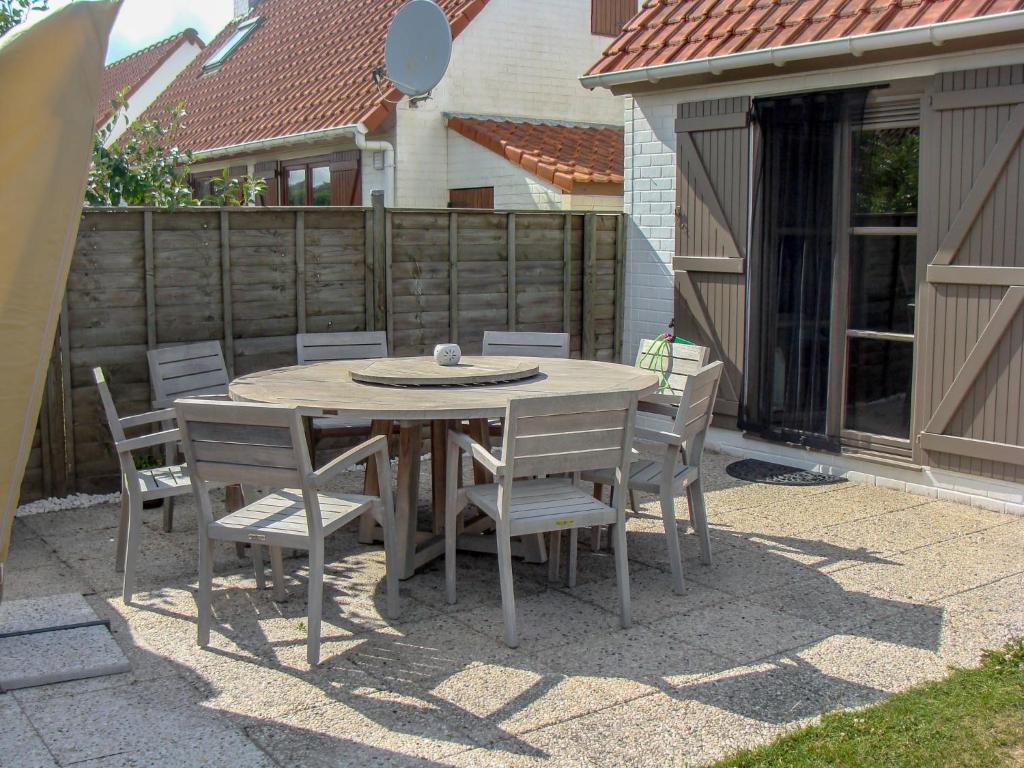 un tavolo e sedie in legno su un patio di Holiday Home Noordzeepark Zeewind 2-1 by Interhome a Mispelburg