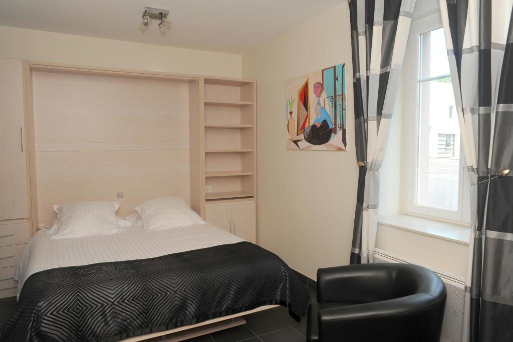 a bedroom with a bed and a chair and a window at Aux Jardins de L'Isle in Vienne