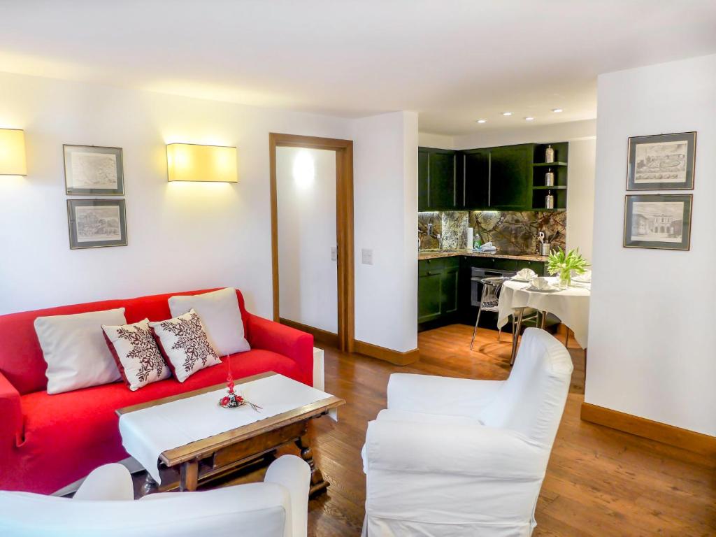 ein Wohnzimmer mit einem roten Sofa und weißen Stühlen in der Unterkunft Apartment Chesa Sonnalpine B 52 by Interhome in St. Moritz