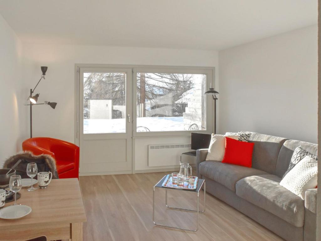 uma sala de estar com um sofá cinzento e uma cadeira vermelha em Studio Diure 0113 by Interhome em Verbier
