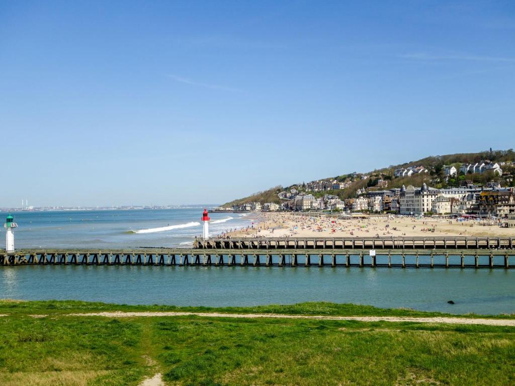 a beach with a pier and a beach with a lighthouse at Studio Les Marinas-8 by Interhome in Deauville