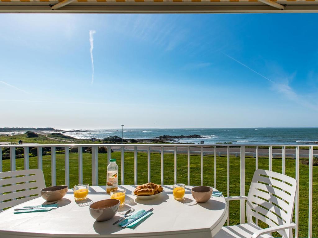 einen Tisch mit Speisen und Getränken auf einem Balkon mit Meerblick in der Unterkunft Studio Les Trois Iles-2 by Interhome in Port-Haliguen