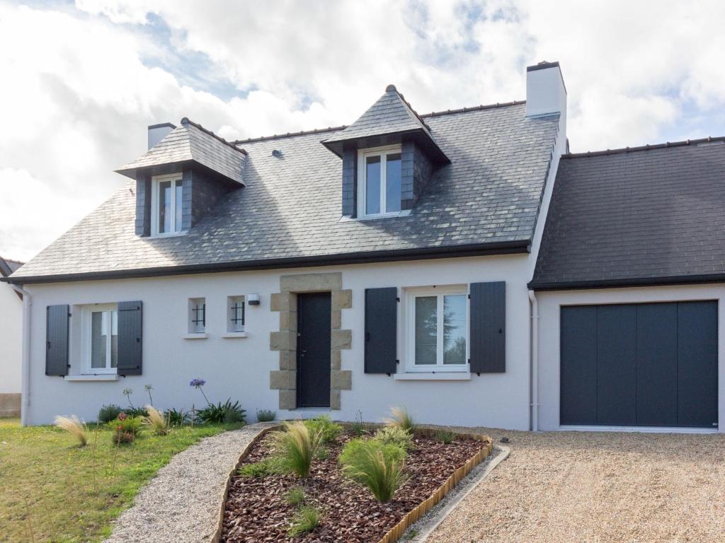 a white house with black shutters and a garage at Holiday Home Pival by Interhome in Port Blanc