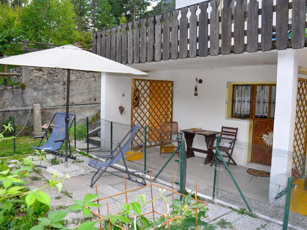 un patio con mesa, sillas y sombrilla en Apartment La Busa-4 by Interhome, en Alleghe
