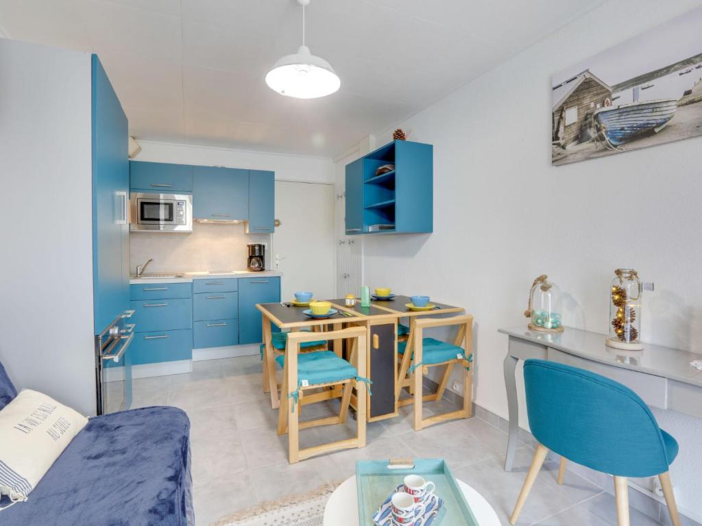 een keuken met blauwe kasten en een tafel en stoelen bij Apartment Les Jardins de l'Océan-41 by Interhome in Pontaillac