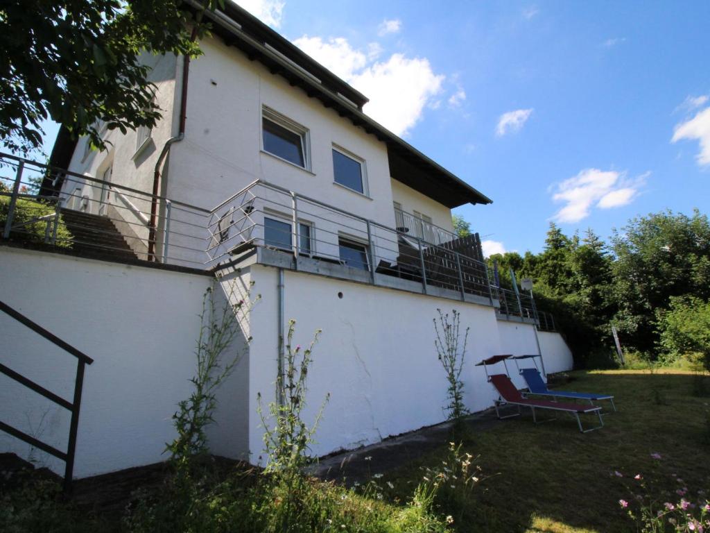 a white house with a bench on the side of it at Apartment Eifelnatur - Haus 3-2 by Interhome in Immerath