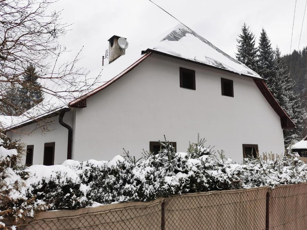 una casa blanca con nieve en el techo en Chalupa U Potoka, en Staré Hory