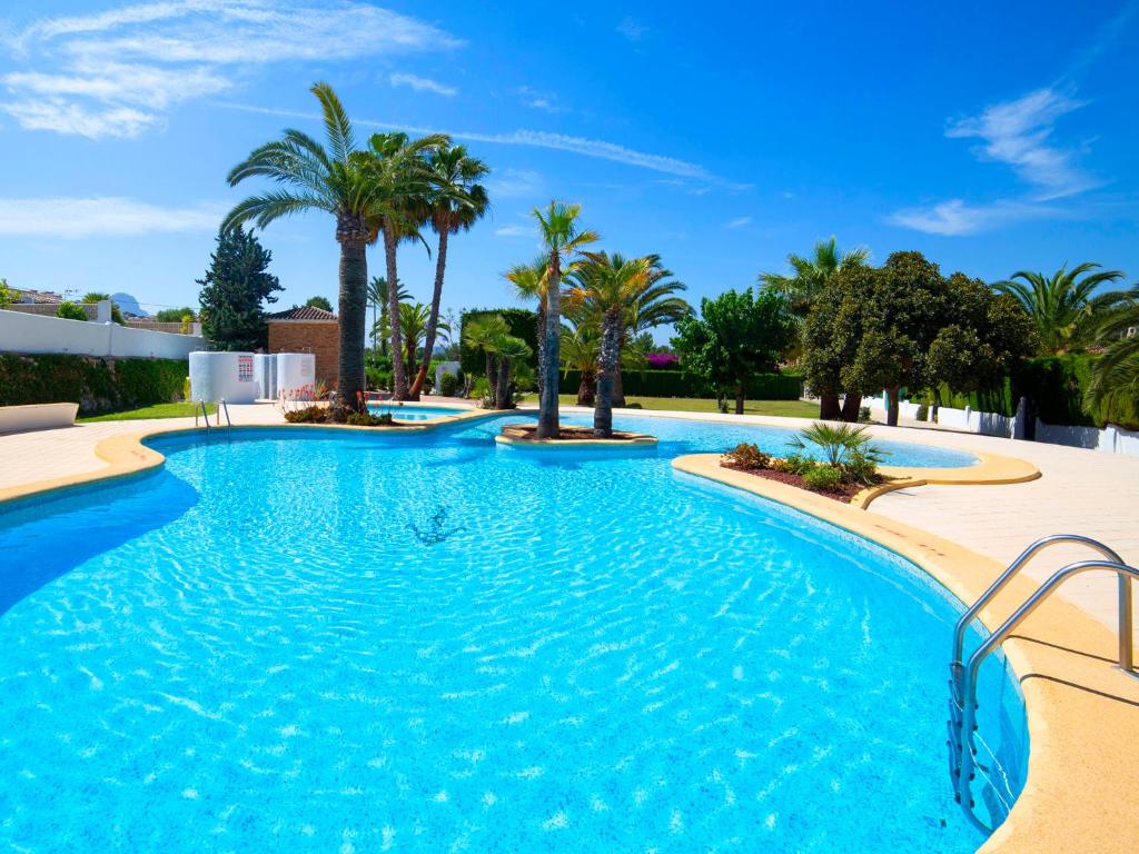 a swimming pool with palm trees in a resort at Holiday Home Rafol by Interhome in Calpe
