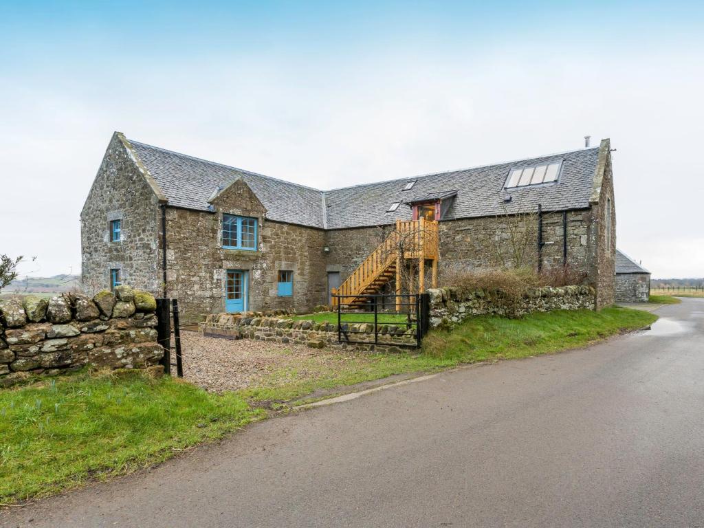 an old stone house with a wooden staircase in front of a road at Holiday Home The Hayloft by Interhome in Edinburgh