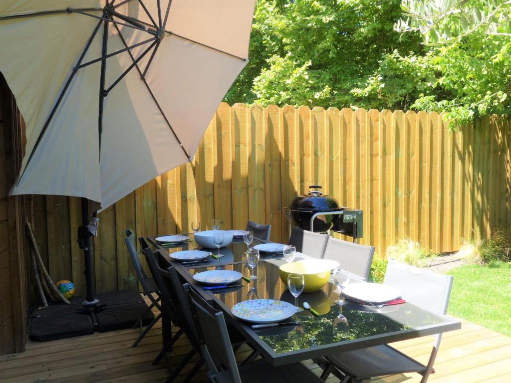 a table with chairs and an umbrella on a patio at Holiday Home Le Chant Des 4 Sirènes by Interhome in La Teste-de-Buch