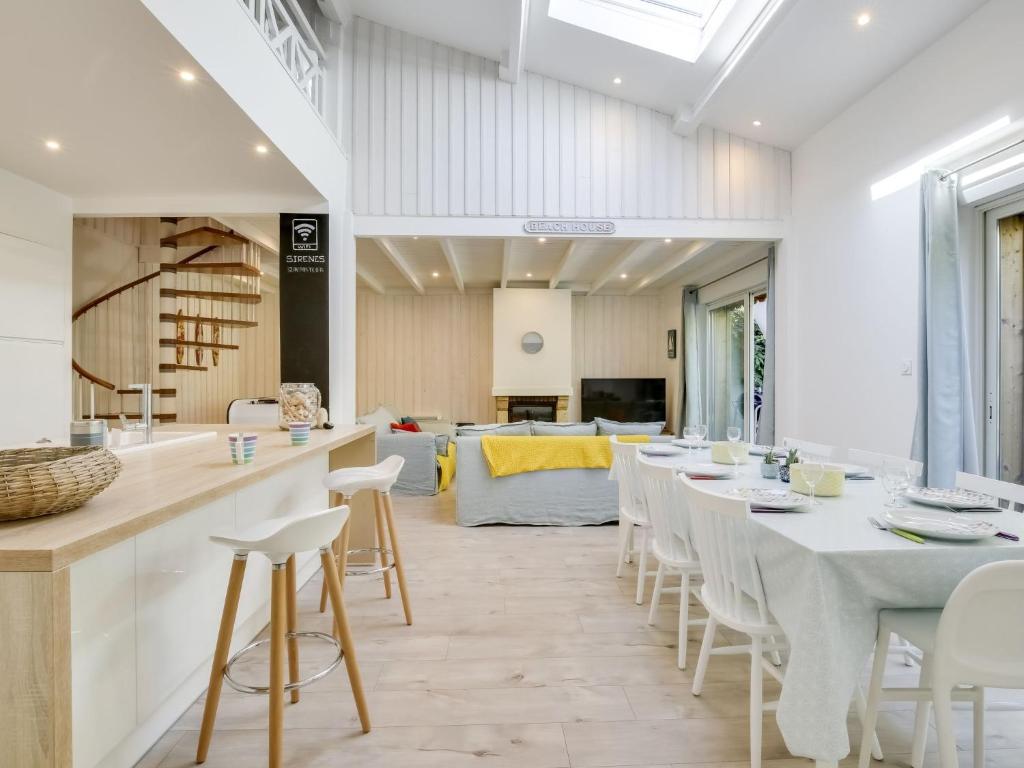 a dining room with a long table and white chairs at Holiday Home Le Chant Des 4 Sirènes by Interhome in La Teste-de-Buch