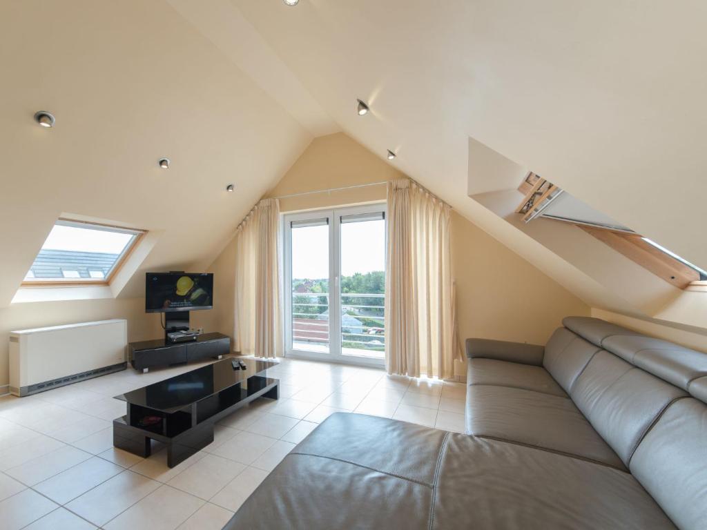 a living room with a couch and a large window at Apartment Goldsands II 402 Top floor with parking by Interhome in De Haan