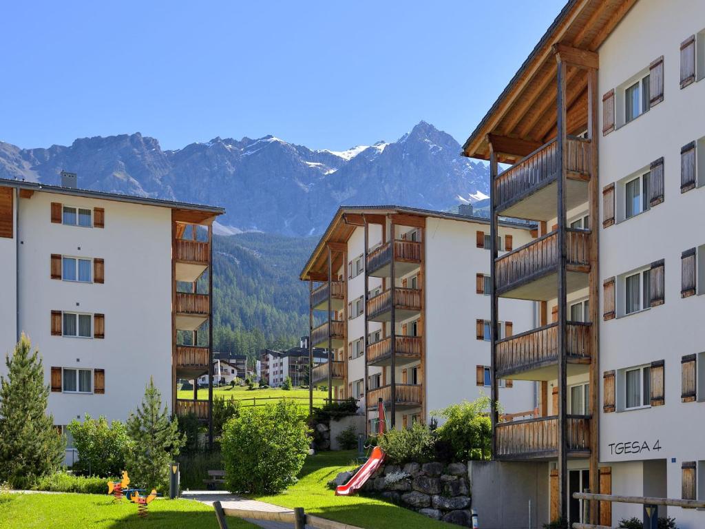 un gruppo di edifici con montagne sullo sfondo di Apartment Surses Alpin-3 by Interhome a Savognin