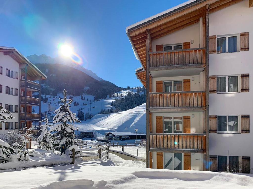 Un edificio en la nieve con el sol detrás. en Apartment Surses Alpin-1 by Interhome, en Savognin