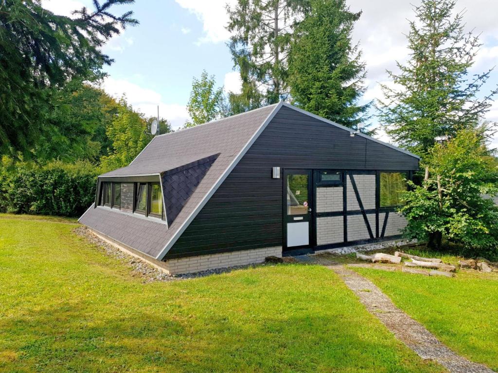 a small house with a black roof on a yard at Holiday Home Waldferienpark Gerolstein-16 by Interhome in Gerolstein