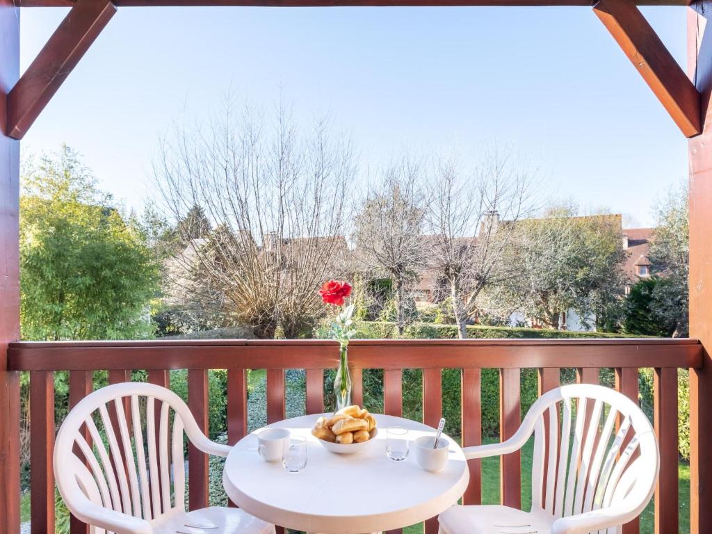 a white table and chairs on a balcony with a red rose at Apartment Domaine de Clairefontaine-3 by Interhome in Deauville