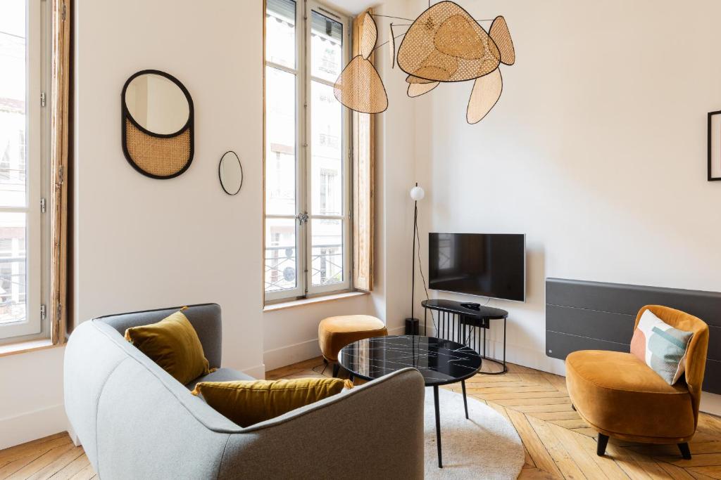 een woonkamer met een bank en stoelen en een tv bij DIFY Bellecour - Centre Ville in Lyon