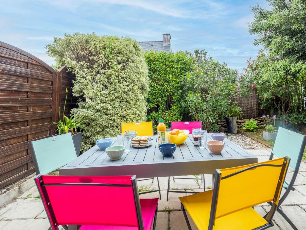 une table en bois avec des chaises colorées sur la terrasse dans l'établissement Holiday Home Résidence Ker Armor by Interhome, à Quiberon