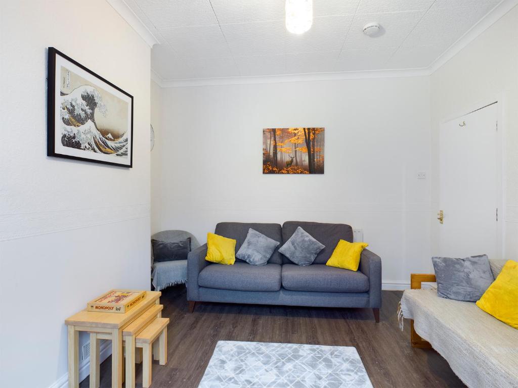uma sala de estar com um sofá azul e almofadas amarelas em Cheerful 3 bedroom home with free parking and WIFI em Chester