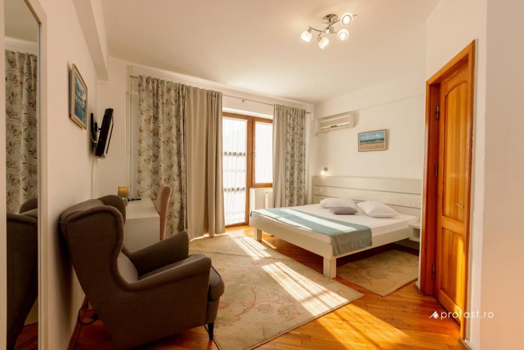 - une chambre avec un lit et une chaise dans l'établissement Vila Belvedere, à Galaţi