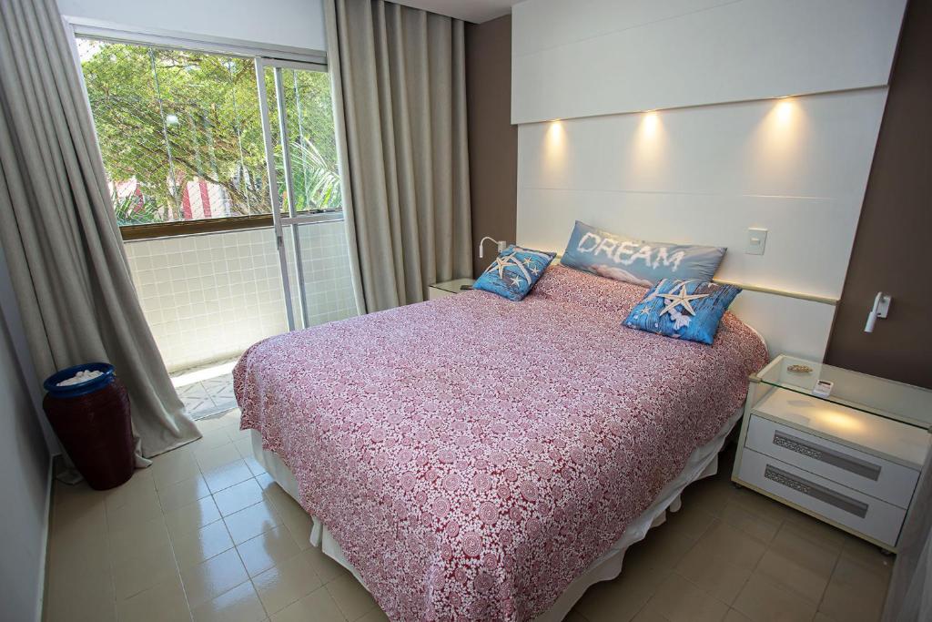 a bedroom with a large bed with a window at Apartamento com Wi-Fi no centro de Guarapari ES in Guarapari