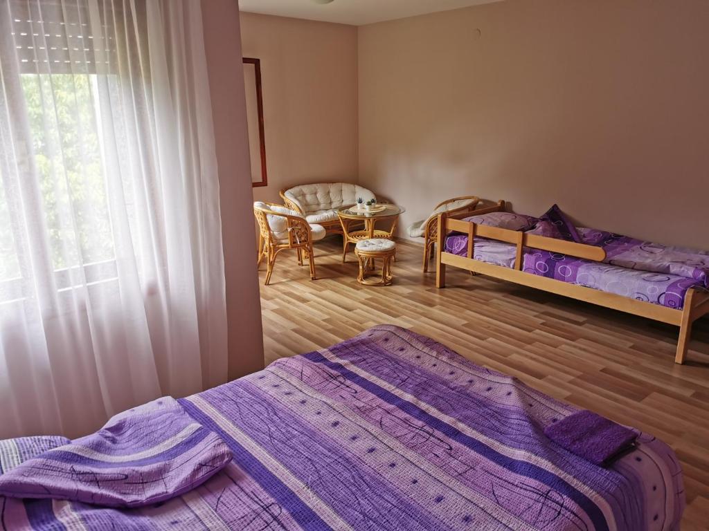 a bedroom with two beds and a table and a window at Jumiko Apartments in Vrnjačka Banja