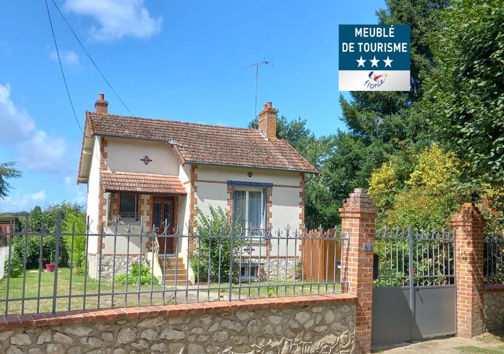 een klein huis met een hek en een bord bij Les Marguerites, maison proche de Chambord in Bracieux