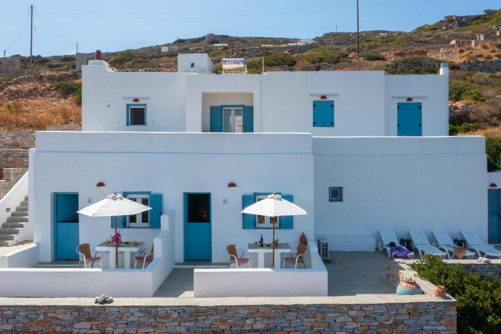 a white building with blue doors and tables and chairs at Skaloto Studios in Artemonas