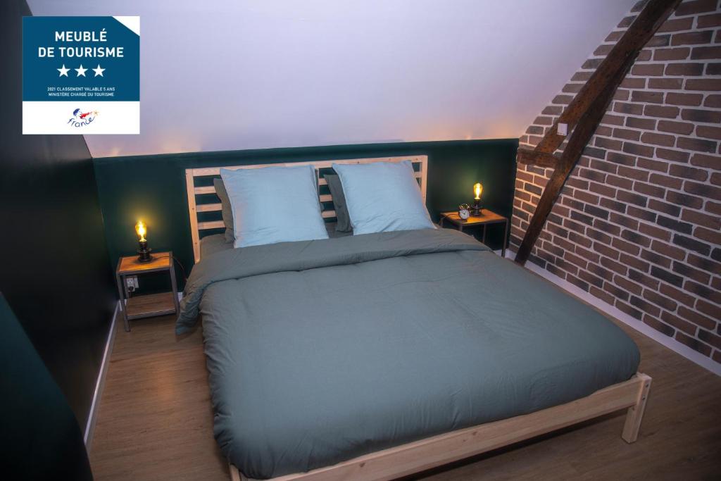 um quarto com uma cama e uma parede de tijolos em L'Atelier Brainois - Meublé de tourisme 3*** em Braine
