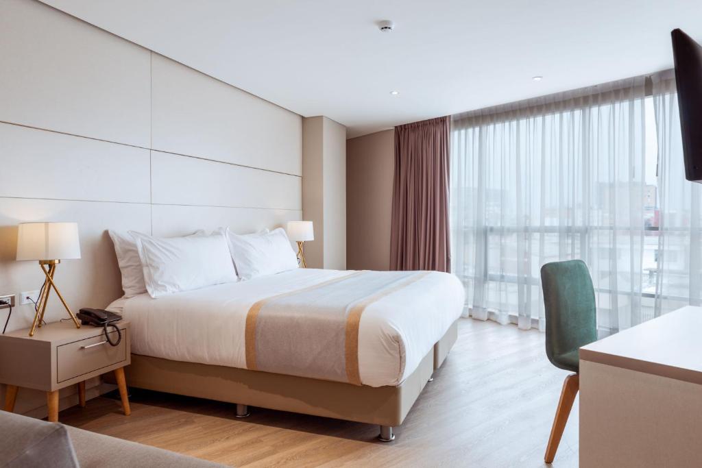 a hotel room with a bed and a large window at Hotel City Bog Corferias in Bogotá