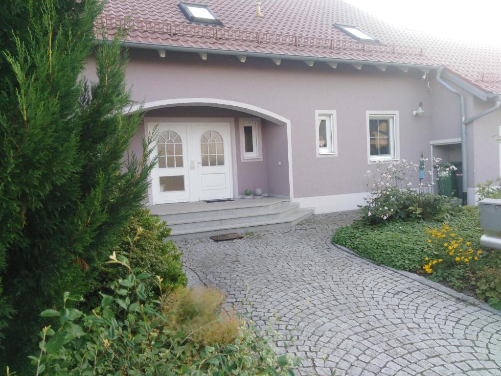 a house with a pathway leading to a white door at Ferienwohnung Lang in Nittenau