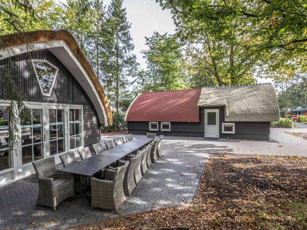 a building with a table and benches in front of it at Beautiful group accommodation at nature reserve in De Bult