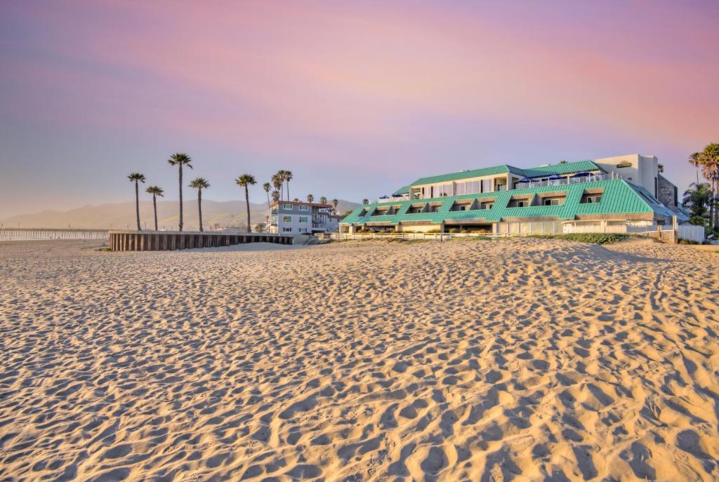 a beach with palm trees and buildings on it at SeaVenture Beach Hotel in Pismo Beach