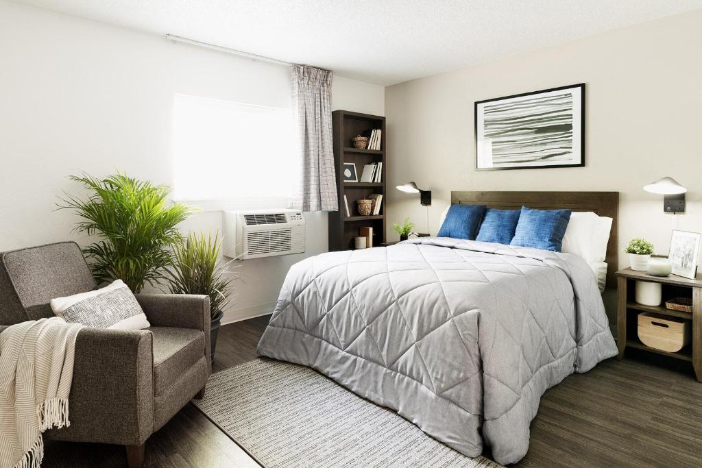 a bedroom with a bed and a chair and a window at InTown Suites Extended Stay Tuscaloosa, AL in Tuscaloosa