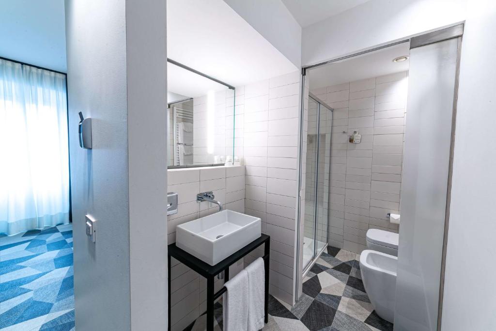 a white bathroom with a sink and a toilet at Hotel Cappello D'Oro, BW Signature Collection in Bergamo