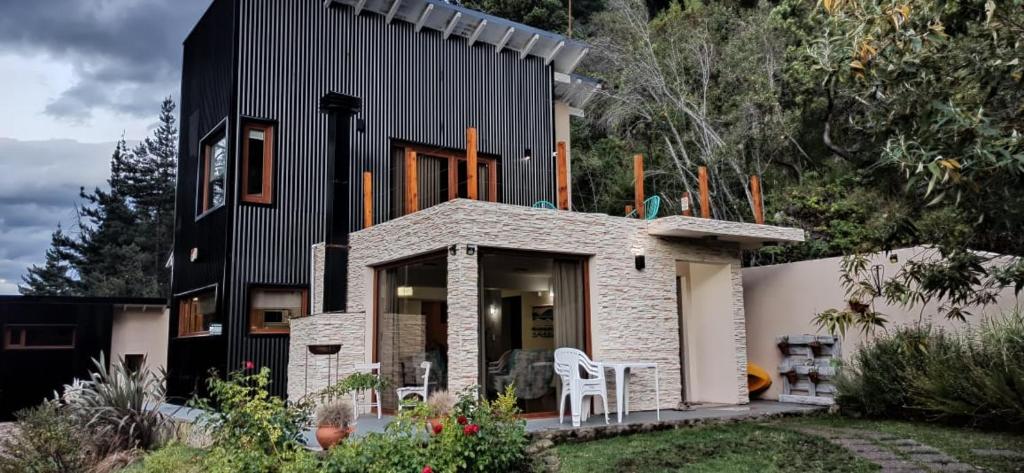 a house with a black roof and a patio at Complejo EL PAÑIL in Lago Puelo