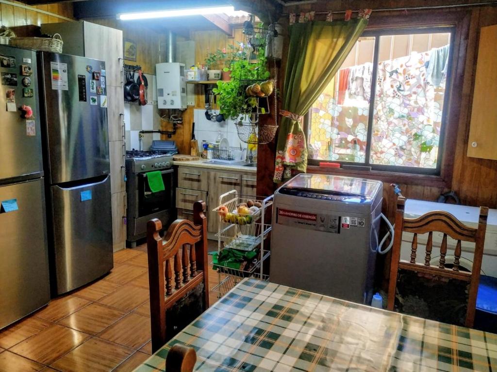 cocina con nevera, mesa y sillas en CABAÑAS MARISOL, en Valdivia