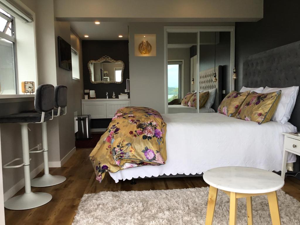 a bedroom with a bed and a mirror and a stool at Spectacular Lake Views in Rotorua