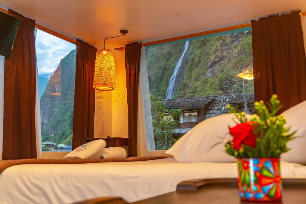 a bedroom with a view of a waterfall through a window at Hotel De Mi Pueblo in Baños