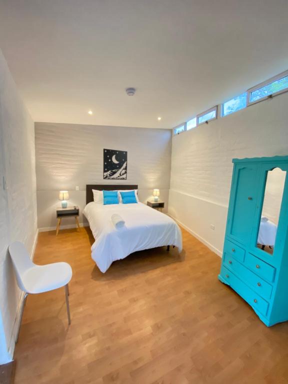 a bedroom with a white bed and a blue cabinet at Springhills Quito Airport in Tababela